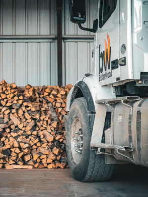 a butlerwood truck parked in front of a wall of stacked firewood