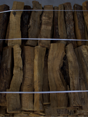 A stack of raw, irregularly shaped wood pieces or bark logs bundled together with thin white strings, filling the entire frame.